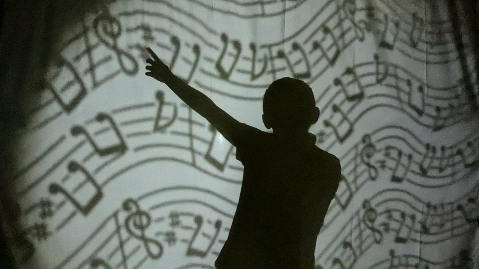 photo d'un atelier de théâtre d'ombre. Ombre corporelle sur fond de partition.