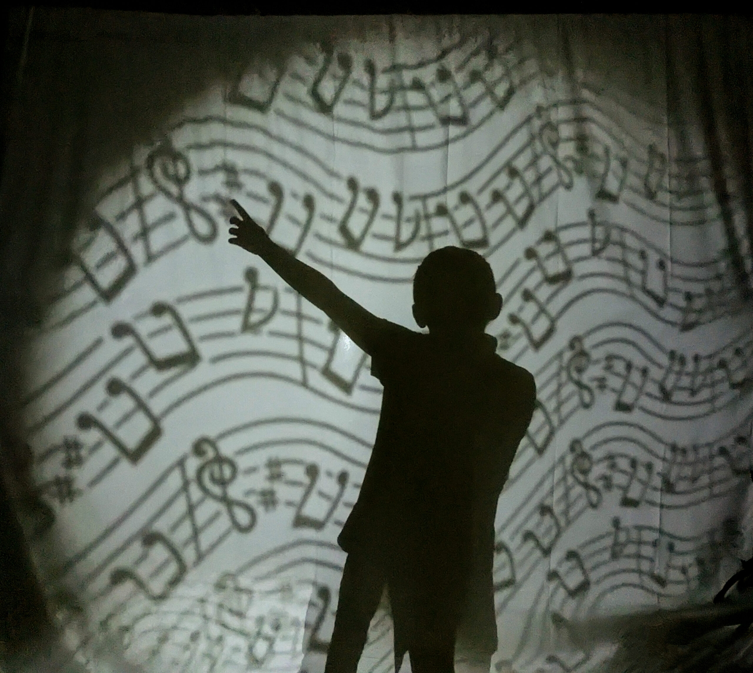 photo d'un atelier de théâtre d'ombre. Ombre corporelle sur fond de partition.